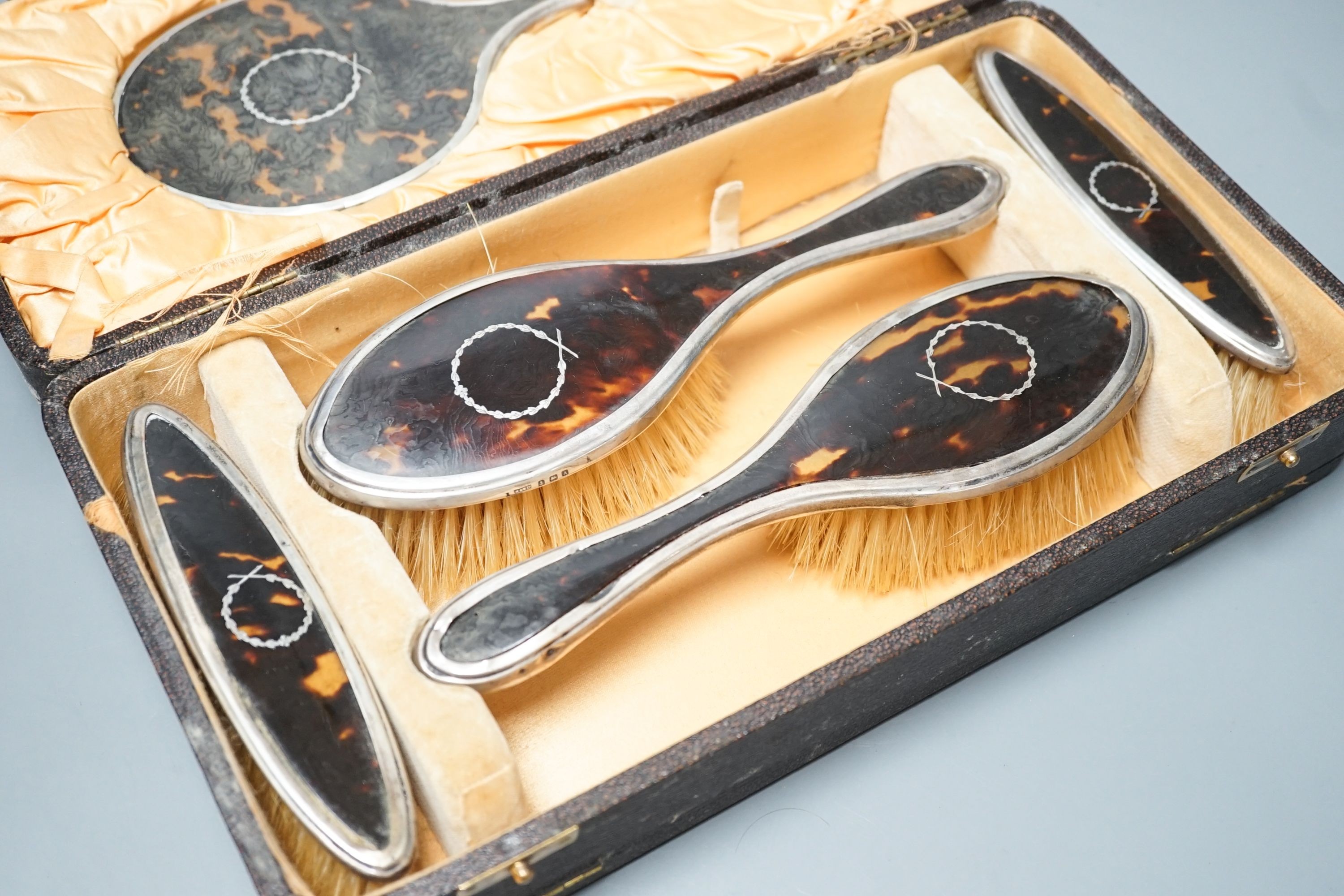 A 1920's cased tortoiseshell and silver mounted mirror and brush set.